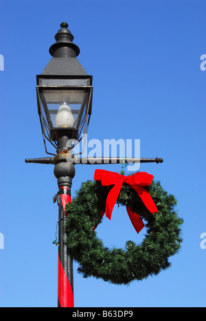 Decorazioni per le vacanze durante il 'Notti ofLights' in St Augustine, Florida includono questa strada lampada decorata con una corona di fiori e di prua. Foto Stock