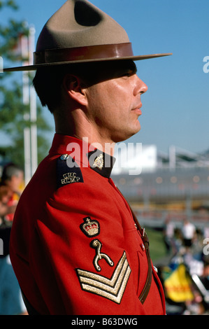 Un Canadese Mountie (GRC) Royal Canadian montato funzionario di polizia indossando il tradizionale rosso Serge uniforme e permanente al attenzione Foto Stock