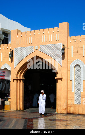 Uomo locali in costume nazionale effettua una chiamata al cancello di ingresso per la Mutrah souq, Moscato, il sultanato di Oman Foto Stock