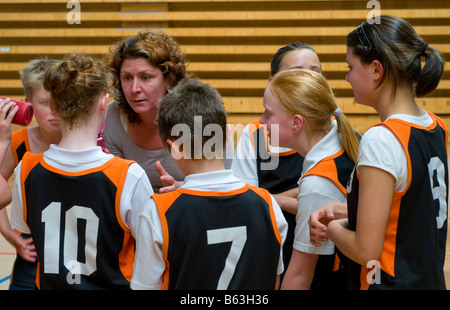 Pullman a discutere di tattiche con i giocatori di un misto di junior scuola primaria squadra di basket Foto Stock