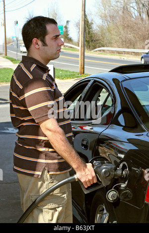 Un uomo di pompaggio a prezzo elevato del gas nella sua auto con un disgustato guarda sul suo volto Foto Stock