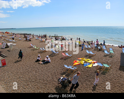 La Brighton Palazzo Marino e il molo è un piacere dal molo di Brighton, Inghilterra. Disseminato di spiaggia con sedie a sdraio e le persone sole. Foto Stock