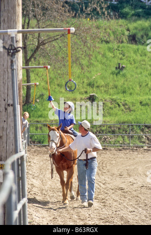 Giovane pilota è assistita in una giostra evento in una comunità horse show. Foto Stock