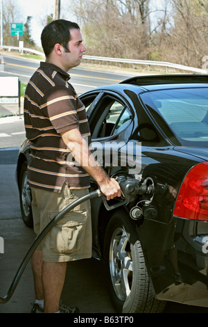 Un uomo di pompaggio a prezzo elevato del gas nella sua auto con un disgustato guarda sul suo volto Foto Stock