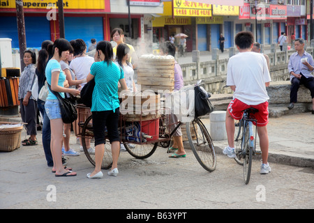 Donna cinese vendere il suo pane appena sfornato sulla strada di Yangshuo, Cina Foto Stock