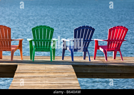 Colorate sedie sul dock che si affaccia su via navigabile. Foto Stock