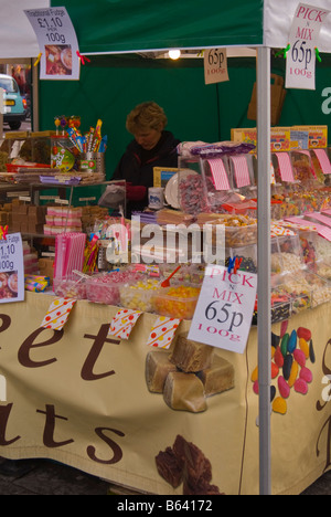 Donna al lavoro su un pick n mix negozio di dolci di stallo di mercato al di fuori del negozio di dolciumi nel Regno Unito Foto Stock