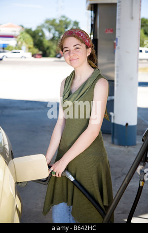 Giovane donna riempie il suo serbatoio di gas è sorridente perché lei aziona un carburante di auto a basso consumo Foto Stock