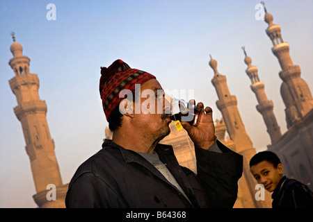 L'Egitto, al Cairo, Cairo Islamico moschea, Madrassa del sultano Hassan (r) e la Moschea di Ar-Rifai (l), l'uomo bere il tè Foto Stock