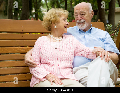 Felice coppia senior si rilassa insieme su una panchina nel parco Foto Stock