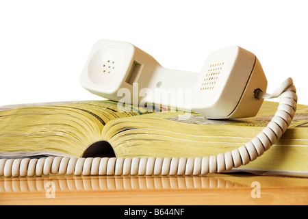 Pagine gialle con ricevitore telefono isolato su bianco Foto Stock