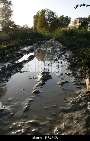 Acqua su terreni fangosi pista rurale lane in un campo vuoto Foto Stock