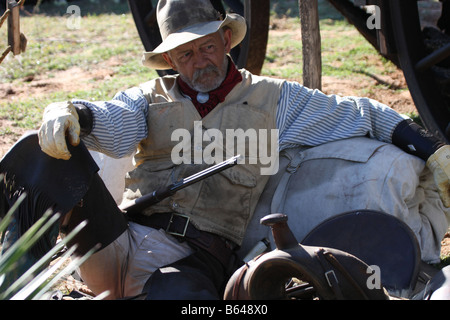 Un vecchio cowboy timer appoggiata contro il suo pack e la sella accanto alla Chuck wagon Foto Stock