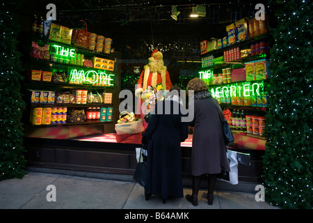 Christmas Shopper sosta per ammirare il Santa Claus in una finestra stagionale di dal grande magazzino Selfridges in Oxford Street Foto Stock