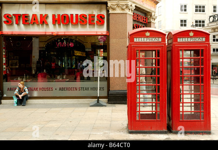 Red cabine telefoniche al di fuori di una steak house in London REGNO UNITO Foto Stock