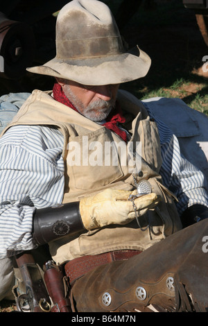 Un vecchio cowboy timer appoggiata contro il suo pack controllando il suo orologio da tasca Foto Stock