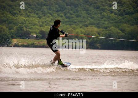 Il freddo,piccante e discontinuo acque del lago,non impedisce a questo uomo da godersi lo sport di wake boarding. Foto Stock