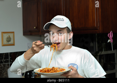 Ragazzo adolescente mangiare spaghetti Foto Stock