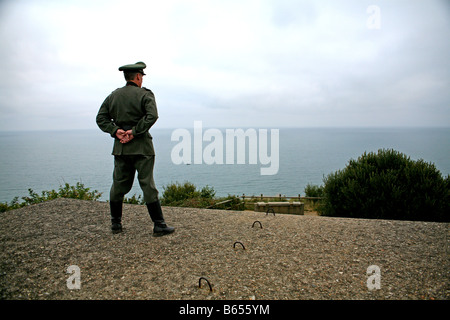 Un attore vestito come un ufficiale tedesco che si affaccia sul canale in lingua inglese e da un tedesco D giorno bunker in Normandia Francia Foto Stock