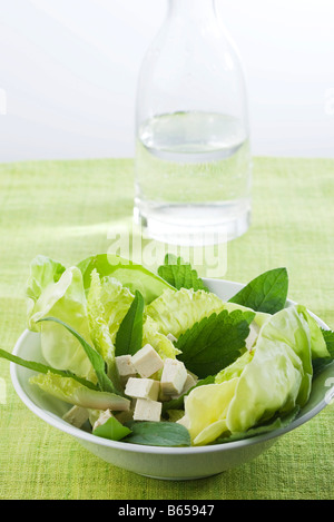Insalata di verdure miste e i cubetti di tofu, caraffa di acqua in background Foto Stock