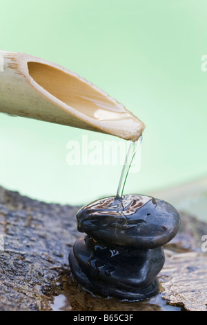 Il tubo di lancio di bambù versando acqua sulla pila di pietre Foto Stock