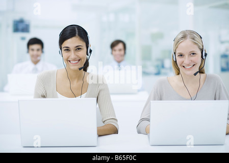 Telemarketers lavorano nei call center, sorridente Foto Stock