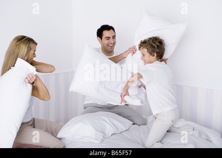 Famiglia avente lotta di cuscini sul letto Foto Stock