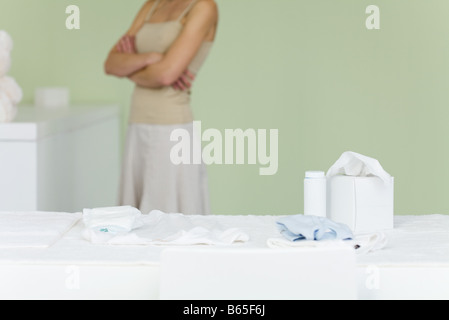 Donna in piedi in vivaio, braccia incrociate, ritagliato Foto Stock