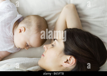 Madre guarda baby napping, giacente insieme sul letto Foto Stock