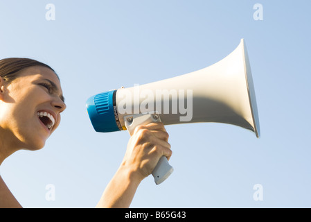 Donna urlando nel megafono, basso angolo visuale, ritagliato Foto Stock