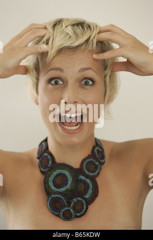 Ritratto di una sorpresa giovane donna con le sue mani sulla testa Foto Stock