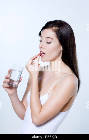 Bella giovane donna su sfondo isolato di mangiare yogurt Foto Stock