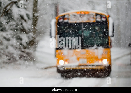 I fiocchi di neve cadono dura come una scuola bus consente di spostarsi tra le strade scivolose. Foto Stock