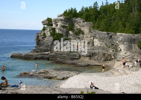 Nuotatori giocare sulle aspre rocce e pietra bianca spiaggia di una isolata insenatura circondata da scogliere. Foto Stock