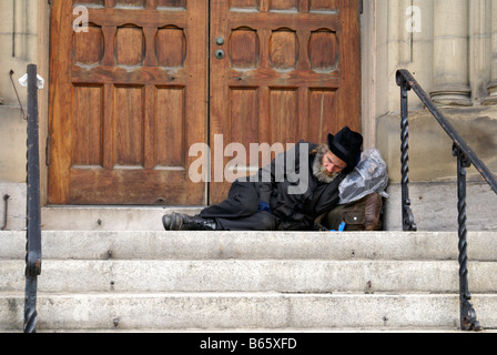 Anziani senzatetto uomo dorme in una porta nel centro cittadino di Montreal, Quebec, Canada Foto Stock