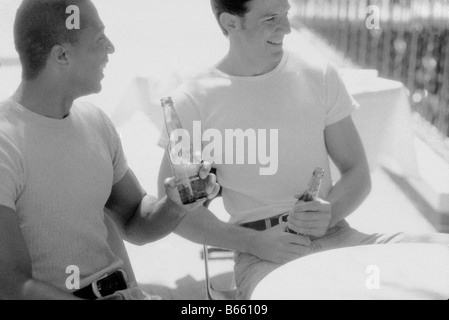 Giovani uomini con bottiglie, ridere, gay Foto Stock