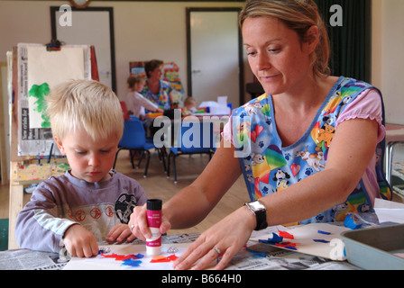 Insegnante di vivaio aiutare un bambino a forme di colla su una foto nella nursery Foto Stock