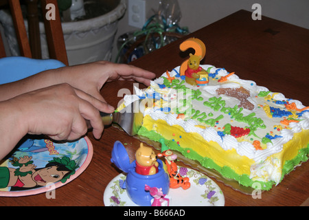 Mani il taglio di un pezzo di torta di compleanno Foto Stock