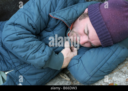 Una vista ingrandita di un senzatetto che dorme sul terreno Foto Stock