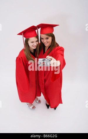 Ritratto in studio di due ragazze in rosso abiti di graduazione Foto Stock