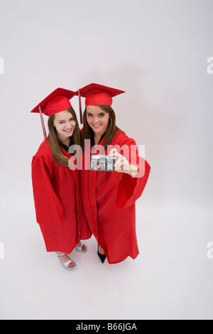 Ritratto in studio di due ragazze in rosso abiti di graduazione Foto Stock