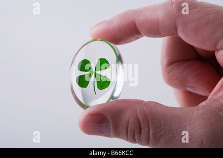 Mano d'uomo azienda quadrifoglio in piccola sfera di vetro Foto Stock