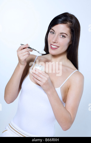 Bella giovane donna su sfondo isolato di mangiare yogurt Foto Stock