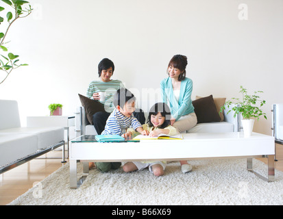 Famiglia di quattro rilassanti nel soggiorno Foto Stock