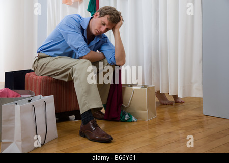 Annoiato uomo in attesa in una stanza per cambiarsi Foto Stock