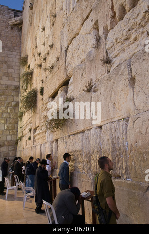 Israele Gerusalemme la città vecchia parete occidentale giovane uomo in bianco e bacia la parete in riverenza con note in crepe Foto Stock