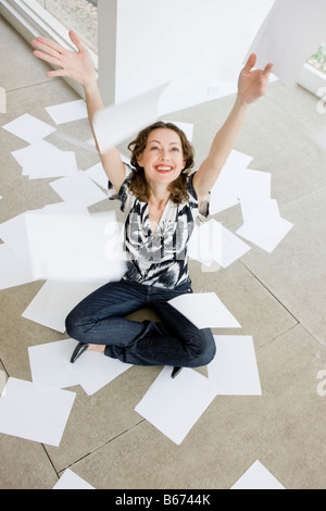 Donna gettando i fogli di carta in aria Foto Stock