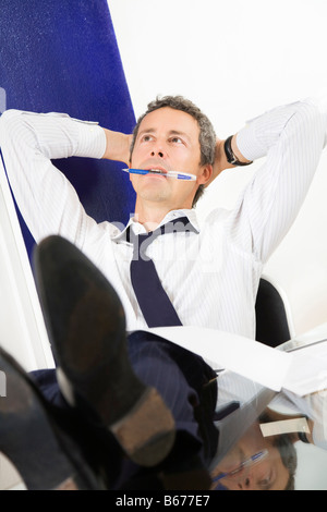 Imprenditore maturo rilassante in office appoggiata piedi sulla scrivania Foto Stock