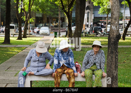 Tre donne vietnamita seduto su una panchina nel parco nella città di Ho Chi Minh, Vietnam Foto Stock