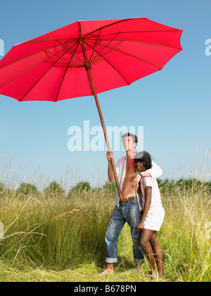 Giovane con un ombrellone in un campo Foto Stock